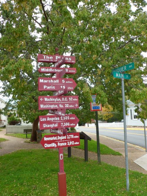 A street corner in The Plains, Virginia, with a sign showing distances to many other cities near and far.